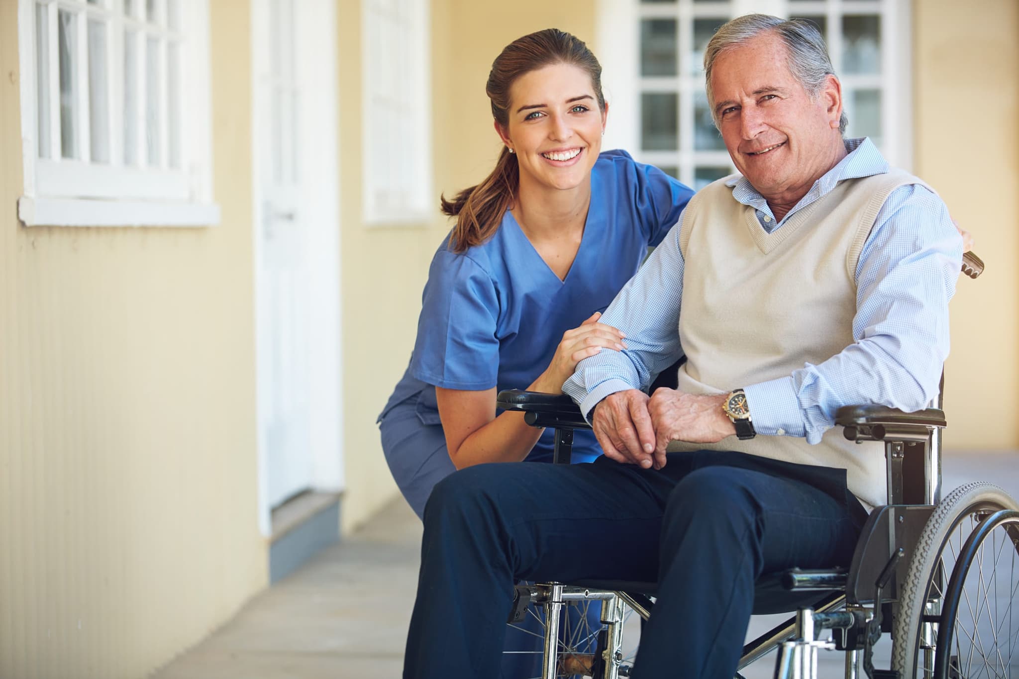 A caregiver assisting a patient using a wheelchair through an accessible clinic entrance